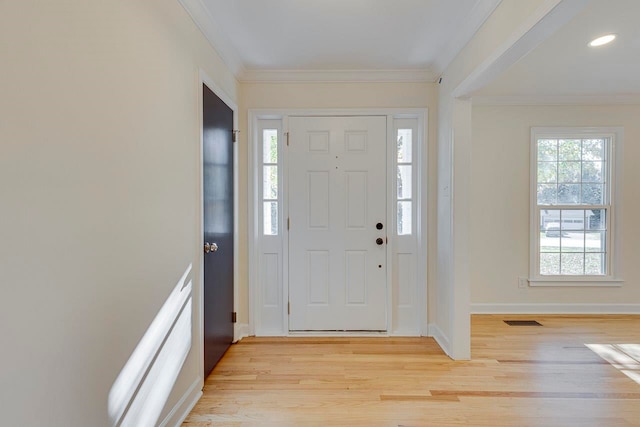 entrance foyer with light hardwood / wood-style floors, crown molding, and a healthy amount of sunlight