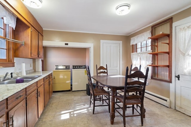 dining space with independent washer and dryer, baseboard heating, ornamental molding, and sink