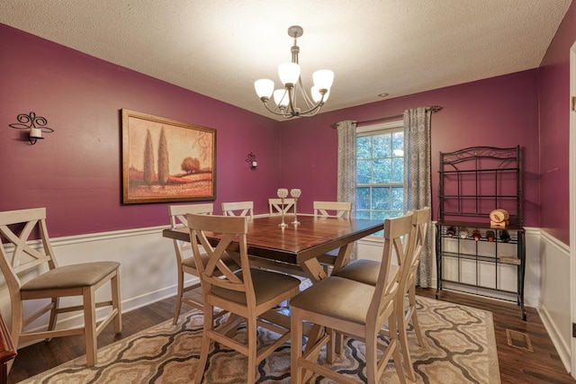 dining area with visible vents, a wainscoted wall, wood finished floors, a textured ceiling, and a chandelier