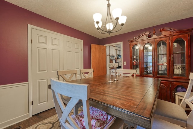 dining area featuring wood finished floors, a textured ceiling, and an inviting chandelier