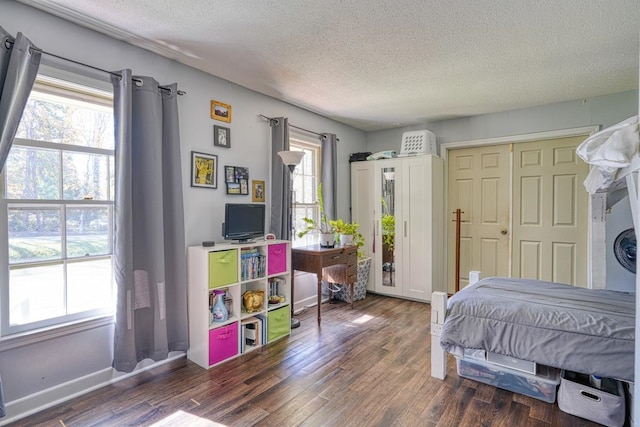 bedroom featuring multiple windows, a textured ceiling, baseboards, and wood finished floors