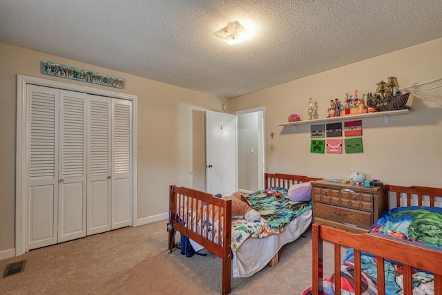 bedroom with a closet, visible vents, light carpet, a textured ceiling, and baseboards