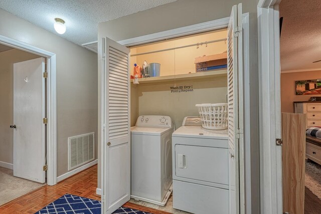 washroom featuring visible vents, washing machine and dryer, a textured ceiling, laundry area, and baseboards