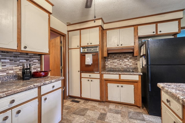 kitchen featuring tasteful backsplash, stone finish floor, a textured ceiling, under cabinet range hood, and black appliances