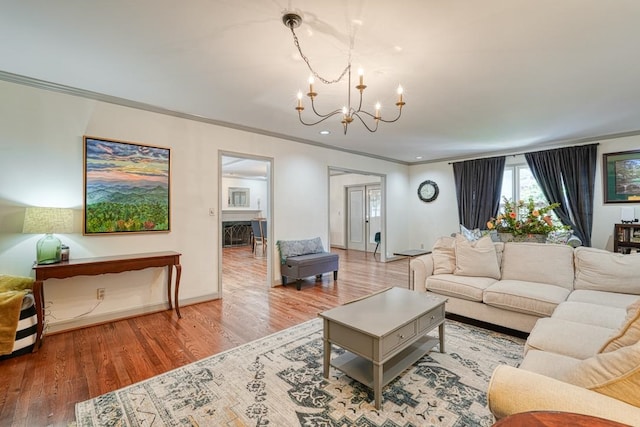 living room with wood-type flooring, crown molding, and a chandelier