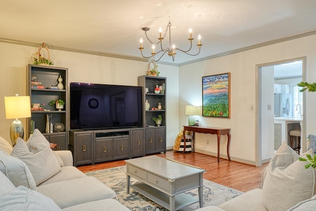 living room featuring a chandelier, light wood-type flooring, and crown molding