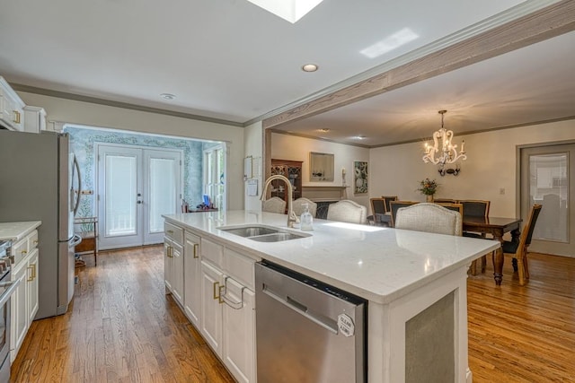 kitchen with light wood-type flooring, stainless steel appliances, sink, a center island with sink, and white cabinets