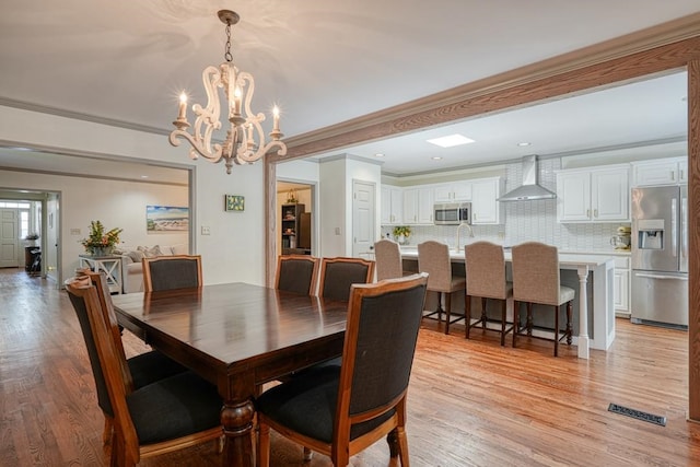 dining area featuring a chandelier, light hardwood / wood-style flooring, and crown molding