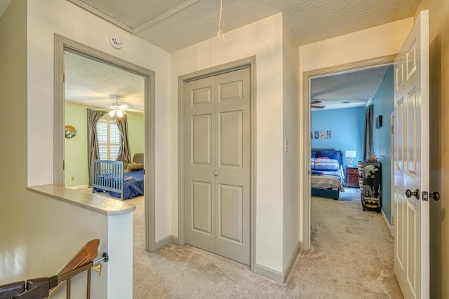 hallway with a textured ceiling and light carpet