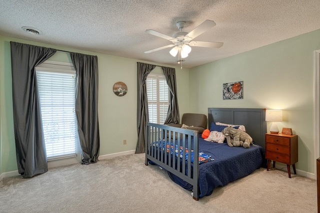 bedroom with ceiling fan, light colored carpet, and a textured ceiling