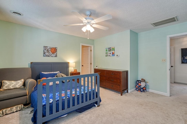 bedroom with a textured ceiling, light colored carpet, and ceiling fan