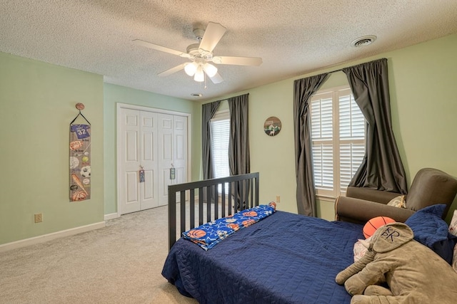 carpeted bedroom with ceiling fan, a closet, and a textured ceiling