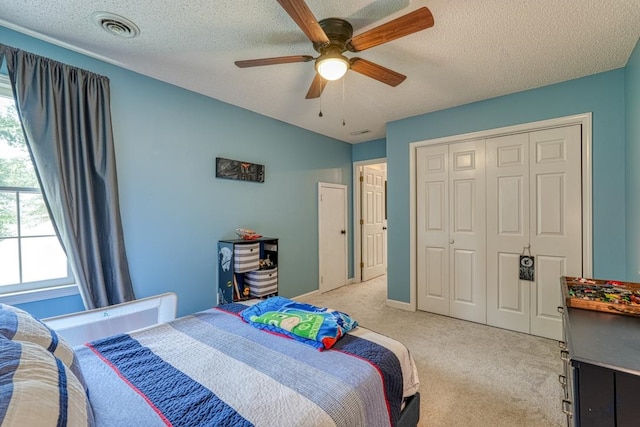 carpeted bedroom with ceiling fan, a textured ceiling, and a closet