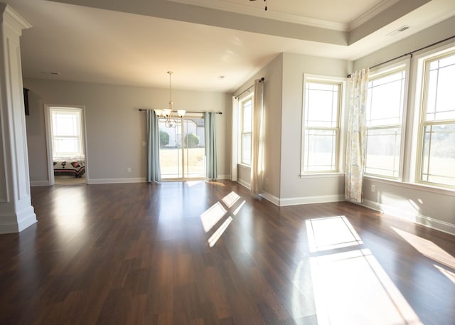 empty room featuring plenty of natural light, dark hardwood / wood-style flooring, ornamental molding, and an inviting chandelier