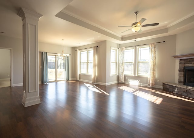 unfurnished living room with a raised ceiling, ornate columns, a wealth of natural light, and dark wood-type flooring