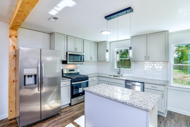 kitchen with appliances with stainless steel finishes, tasteful backsplash, dark wood-type flooring, sink, and decorative light fixtures