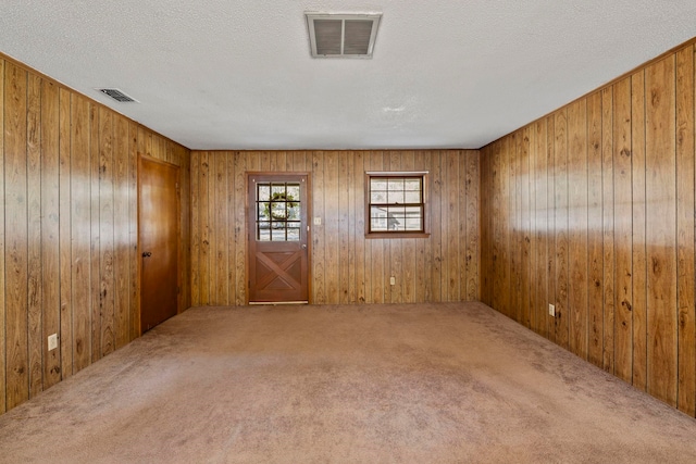 carpeted empty room featuring wood walls and a textured ceiling