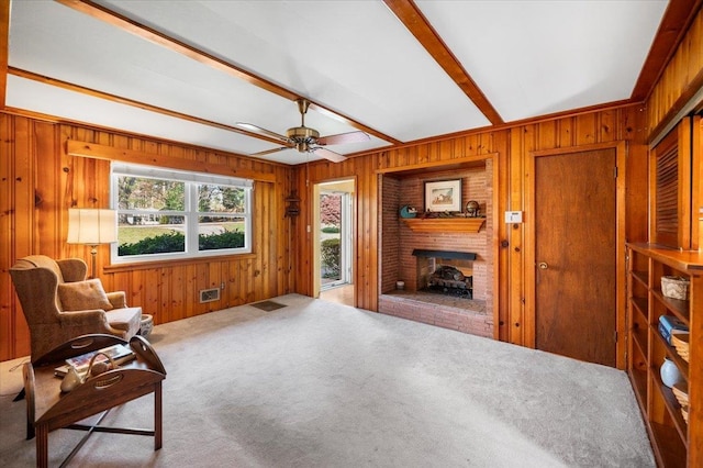 sitting room featuring a fireplace, a healthy amount of sunlight, and wood walls