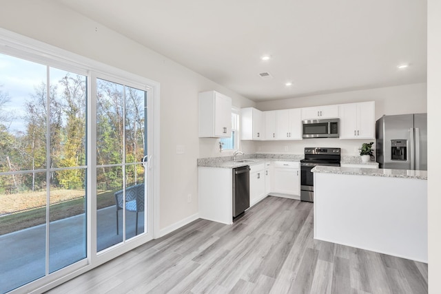 kitchen with white cabinetry, sink, light stone countertops, light hardwood / wood-style flooring, and appliances with stainless steel finishes