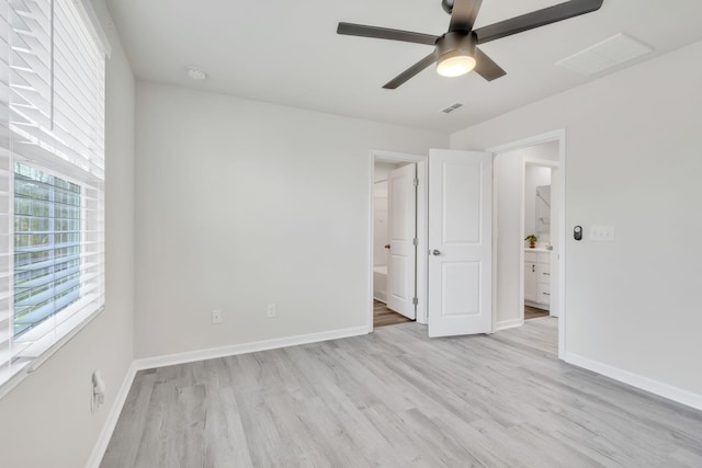 unfurnished bedroom with ceiling fan, ensuite bath, light hardwood / wood-style flooring, and multiple windows