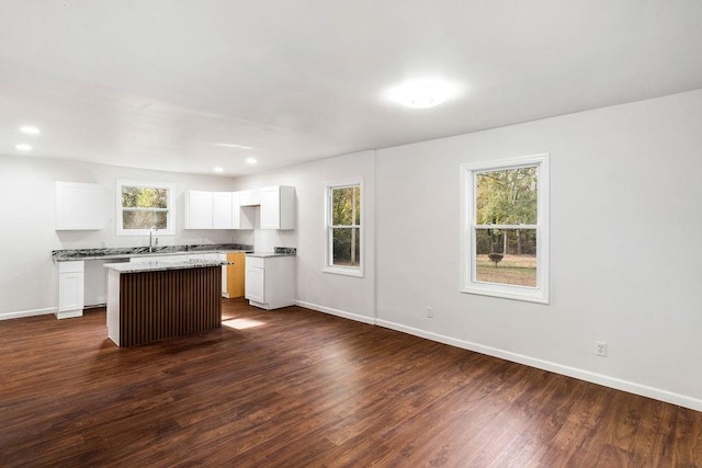 kitchen featuring white cabinets, dark hardwood / wood-style flooring, a kitchen island, and a healthy amount of sunlight