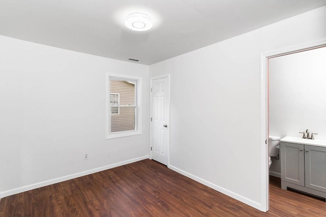 unfurnished bedroom featuring dark wood-type flooring and sink