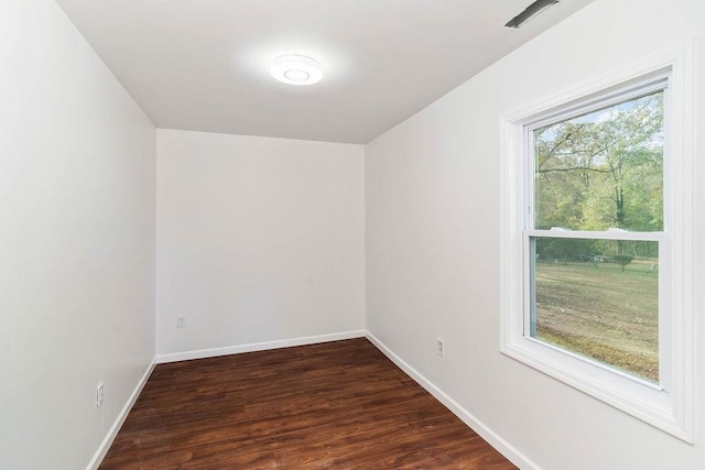 spare room with plenty of natural light and dark wood-type flooring