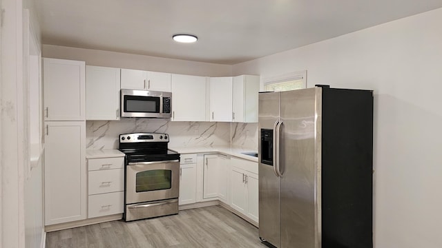 kitchen featuring white cabinets, backsplash, light wood-type flooring, and stainless steel appliances