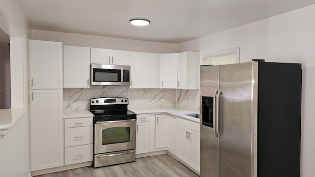 kitchen with stainless steel appliances, white cabinetry, tasteful backsplash, and light hardwood / wood-style floors