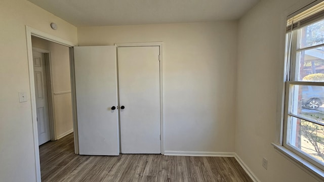 unfurnished bedroom with multiple windows, a closet, and hardwood / wood-style floors