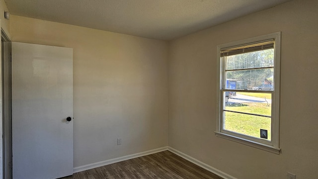 unfurnished room featuring dark wood-type flooring and a textured ceiling