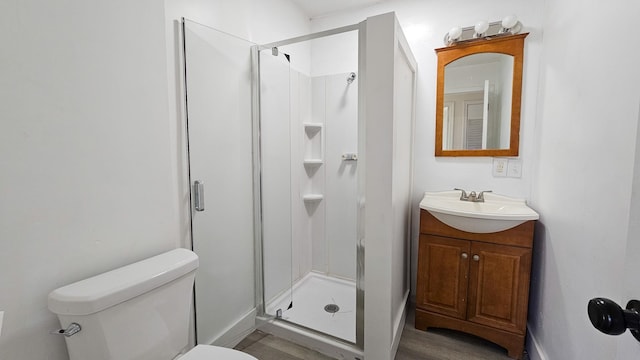 bathroom with hardwood / wood-style floors, vanity, toilet, and a shower with shower door