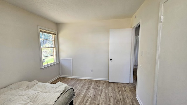 bedroom featuring a textured ceiling and light hardwood / wood-style flooring