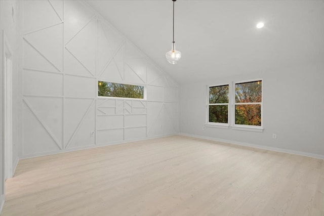 empty room with light hardwood / wood-style floors and vaulted ceiling