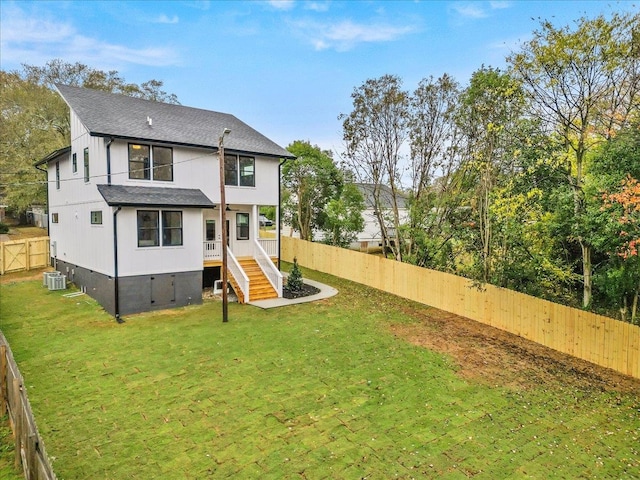 rear view of property featuring a lawn and cooling unit