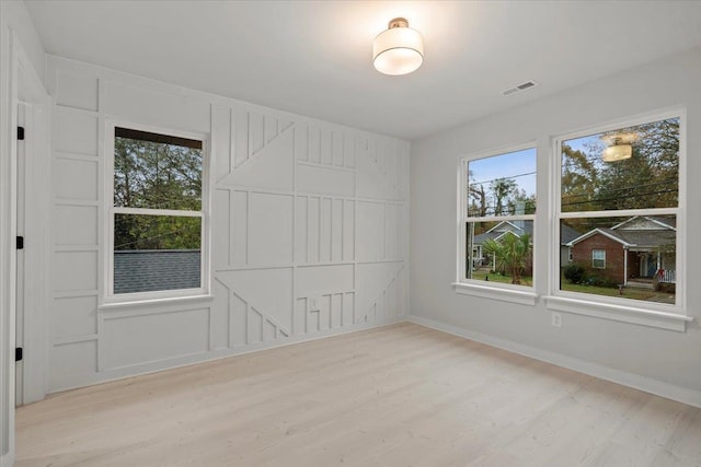 spare room with light wood-type flooring and a wealth of natural light