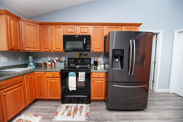 kitchen featuring light hardwood / wood-style floors, vaulted ceiling, and black appliances