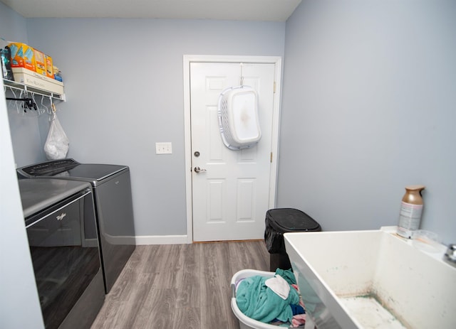 laundry room with separate washer and dryer, hardwood / wood-style flooring, and sink