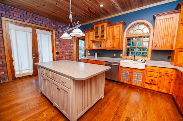 kitchen featuring dishwasher, a kitchen island, brick wall, and sink