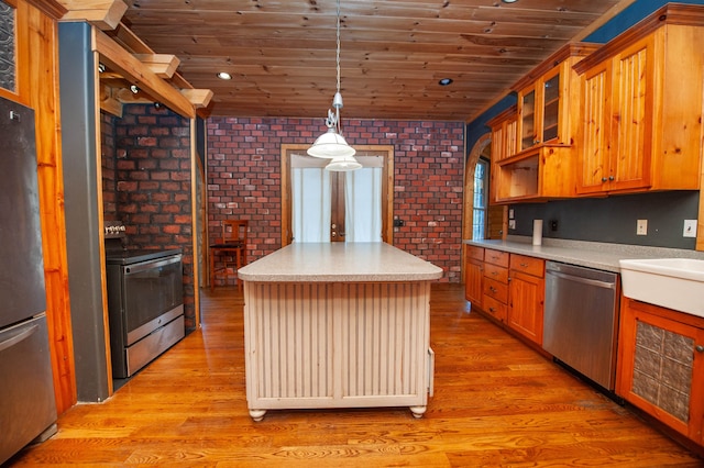 kitchen with a kitchen island, light wood-type flooring, stainless steel appliances, and brick wall