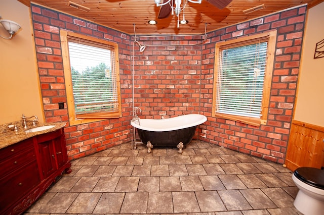 bathroom with a bath, vanity, wooden ceiling, and brick wall