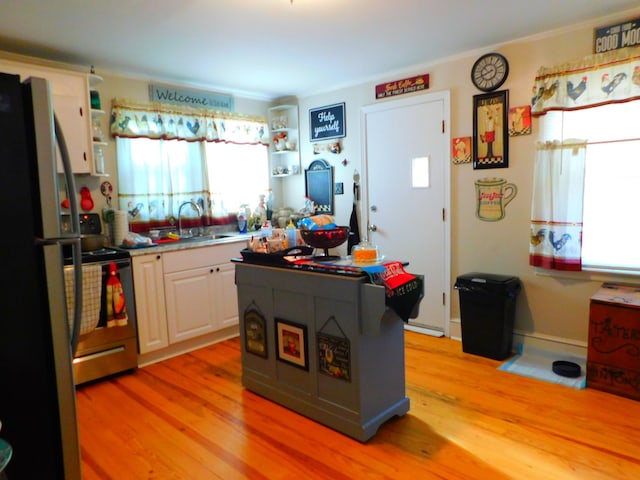 kitchen with sink, refrigerator, stainless steel range with electric stovetop, and light wood-type flooring