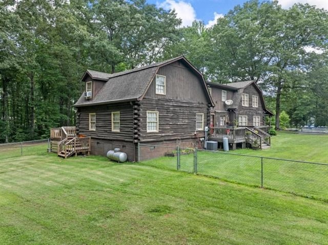 rear view of property featuring a lawn, central AC unit, and a wooden deck