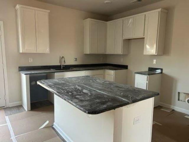 kitchen with baseboards, white cabinets, a sink, and a kitchen breakfast bar