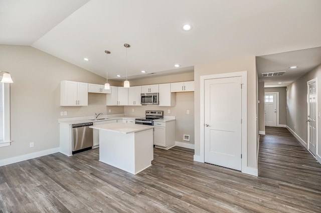 kitchen with white cabinetry, a center island, stainless steel appliances, decorative light fixtures, and hardwood / wood-style flooring