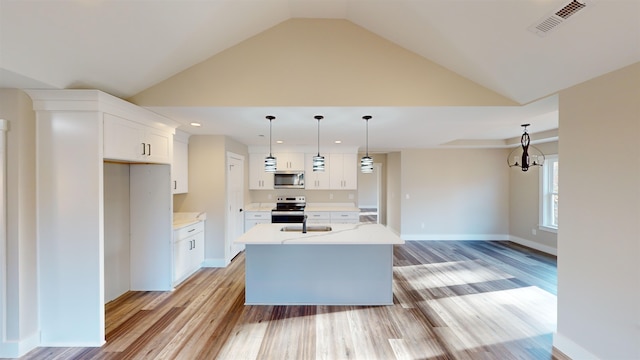 kitchen featuring pendant lighting, a kitchen island with sink, white cabinets, light hardwood / wood-style flooring, and stainless steel appliances