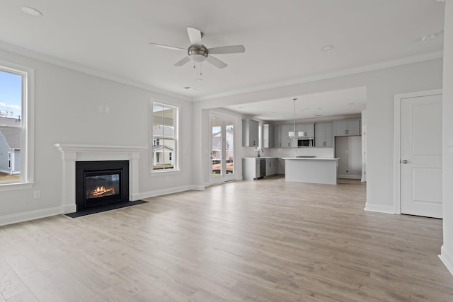 unfurnished living room featuring crown molding, ceiling fan, and light hardwood / wood-style floors