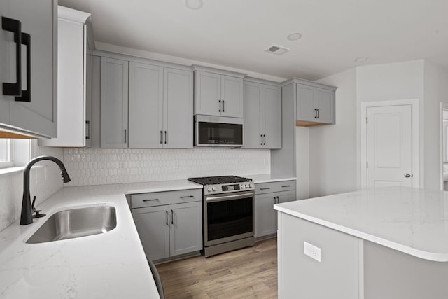 kitchen featuring gray cabinetry, sink, stainless steel appliances, and light wood-type flooring