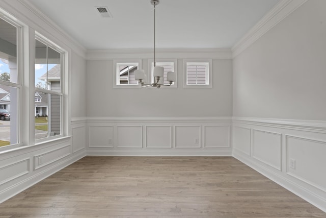 unfurnished dining area featuring a wealth of natural light, ornamental molding, and a notable chandelier