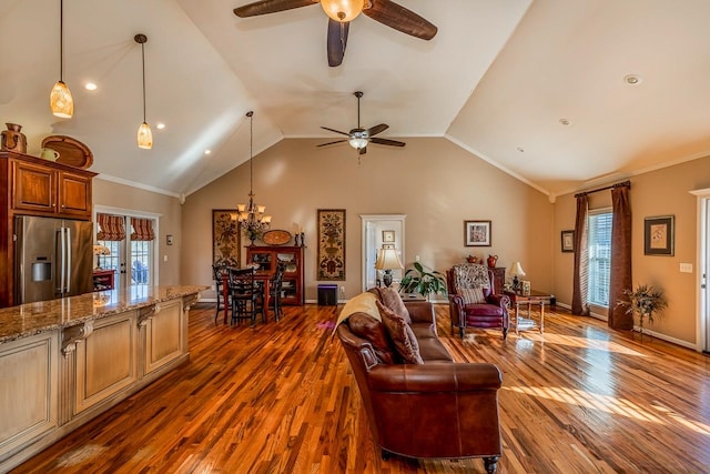 living room featuring dark wood-type flooring, a healthy amount of sunlight, and ceiling fan with notable chandelier